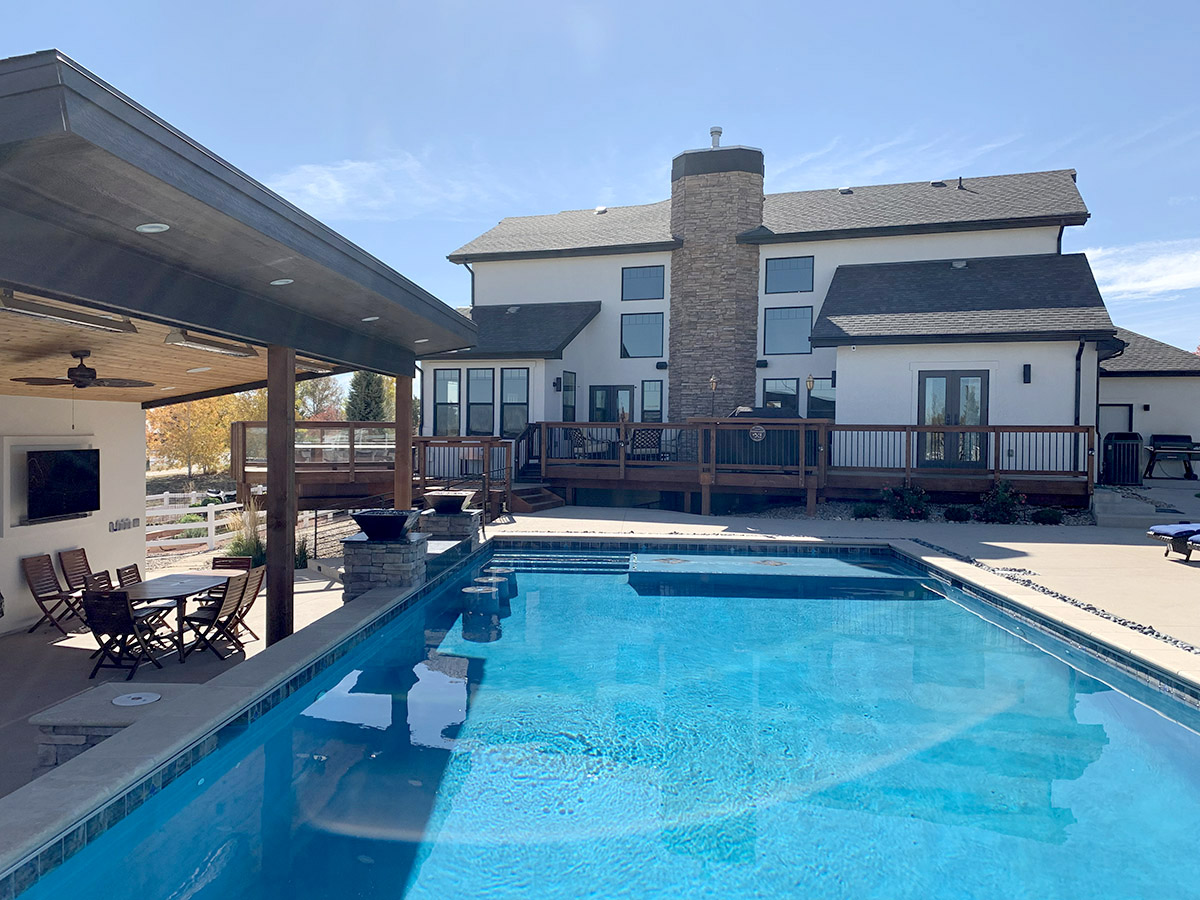 a backyard oasis with pool, covered area, and cuastom deck